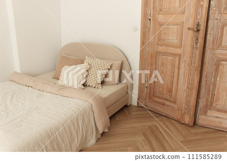 Cozy bed with pillows and blanket in room with old wooden door and floor 111585289