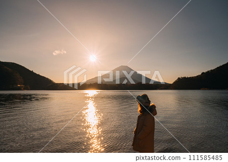 A girl greets the sunrise from the foot of Mt. Fuji A girl greets the sunrise from the foot of Mt. Fuji 111585485