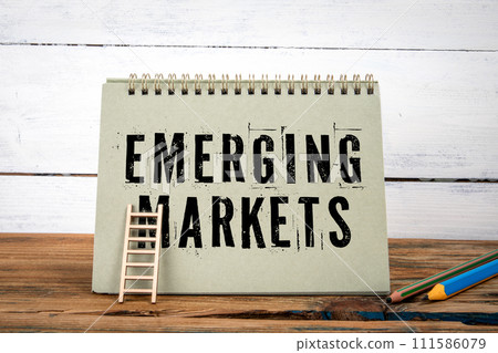 Emerging Markets. Green notepad on wooden texture table and white background Emerging Markets. Green notepad on wooden texture table and white background 111586079