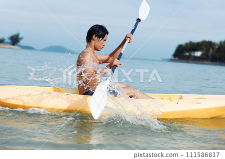 Serene Summer Fun: Asian Man Enjoying Kayaking Adventure on Tropical Beach Serene Summer Fun: Asian Man Enjoying Kayaking Adventure on Tropical Beach 111586817