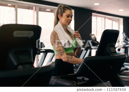 Beautiful muscular woman exercising on treadmill at the gym. Beautiful muscular woman exercising on treadmill at the gym. 111587430
