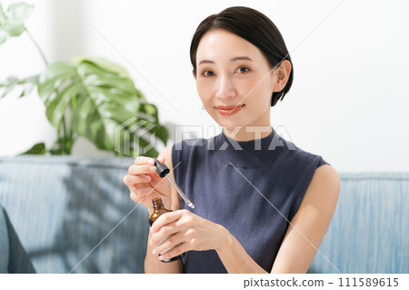 A woman dripping beauty serum on her hands 111589615
