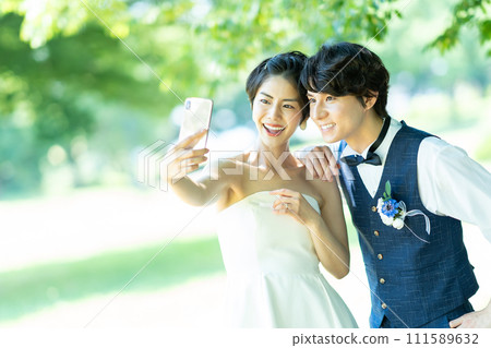 Bride and groom taking photos with smartphone 111589632