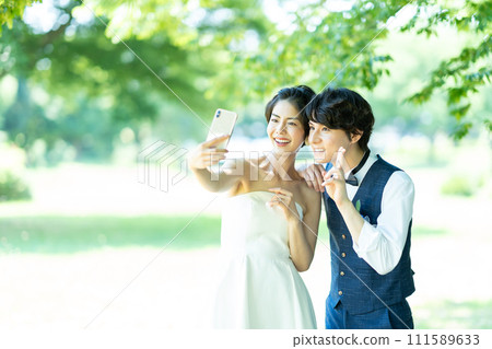Bride and groom taking photos with smartphone 111589633