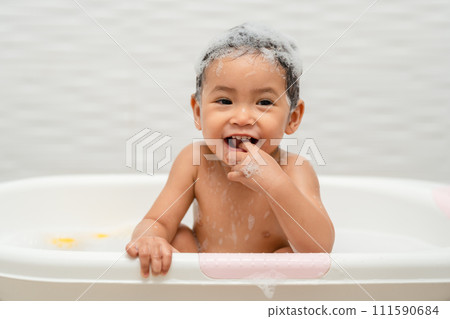 happy infant baby take a bath and playing with foam bubbles in bathtub 111590684