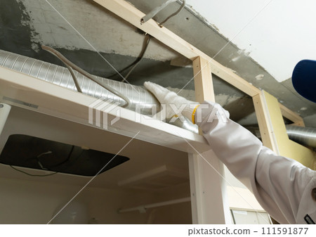 Renovation work: worker checking the duct hose in the ceiling Renovation work: worker checking the duct hose in the ceiling 111591877