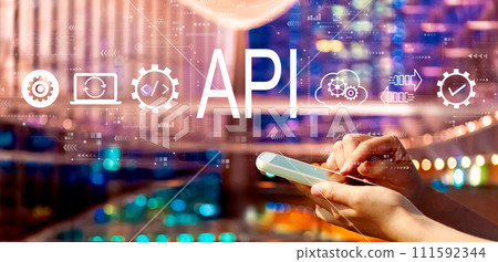 API - application programming interface concept with person using a smartphone in city at night API - application programming interface concept with person using a smartphone in city at night 111592344