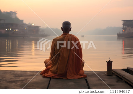 An old yogi was meditating on the bank of the Ganges River. It was quiet amidst the morning sunshine. Behind him is the view of Varanasi. It is a symbol of peace, tranquility and faith in Hinduism. An old yogi was meditating on the bank of the Ganges River. It was quiet amidst the morning sunshine. Behind him is the view of Varanasi. It is a symbol of peace, tranquility and faith in Hinduism. 111594627