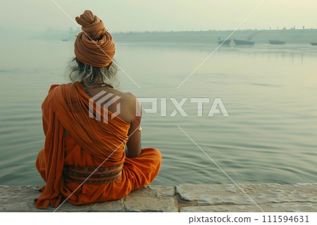 An old yogi was meditating on the bank of the Ganges River. It was quiet amidst the morning sunshine. Behind him is the view of Varanasi. It is a symbol of peace, tranquility and faith in Hinduism. 111594631