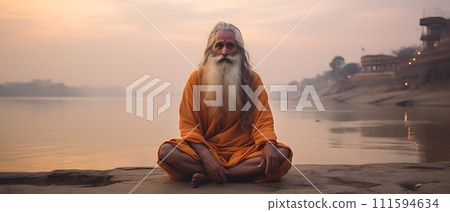 An old yogi was meditating on the bank of the Ganges River. It was quiet amidst the morning sunshine. Behind him is the view of Varanasi. It is a symbol of peace, tranquility and faith in Hinduism. An old yogi was meditating on the bank of the Ganges River. It was quiet amidst the morning sunshine. Behind him is the view of Varanasi. It is a symbol of peace, tranquility and faith in Hinduism. 111594634
