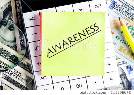 AWARENESS word writingon a yellow sticker on the calculator against the background of banknotes 111596678