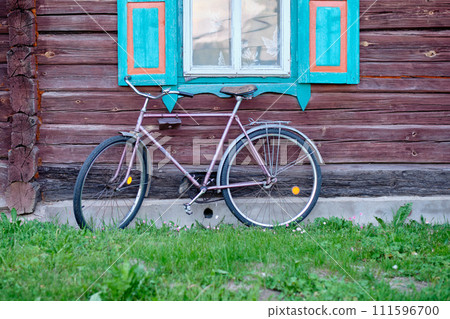 An old bicycle on the background of an old house. The concept of developing and replacing everything old with new 111596700