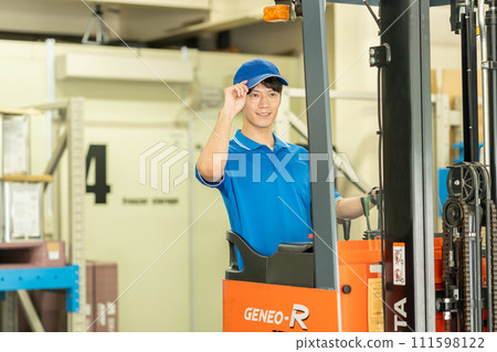 A man driving a forklift in a warehouse 111598122