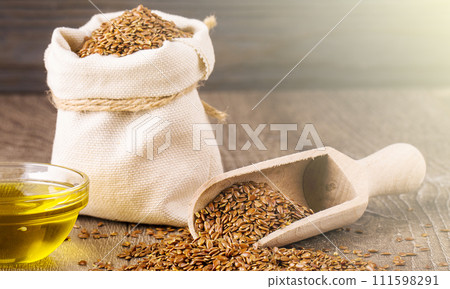 Sesame seeds in sack and bottle of oil on wooden rustic table on sunlight 111598291