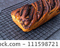 A whole bun with poppy seed filling lies on a hot stand, black background, top view 111598721