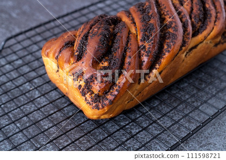 A whole bun with poppy seed filling lies on a hot stand, black background, top view 111598721