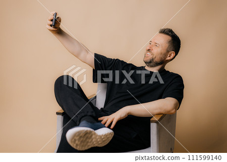 man smiling and taking a selfie and blog isolated on beige background 111599140