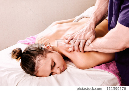 Male masseur gives back massage to young European woman in spa beauty salon. 111599376