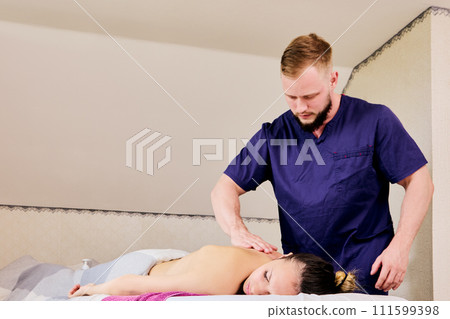 Home visit of a massage therapist with massage table for back massage of young Caucasian woman. Home visit of a massage therapist with massage table for back massage of young Caucasian woman. 111599398