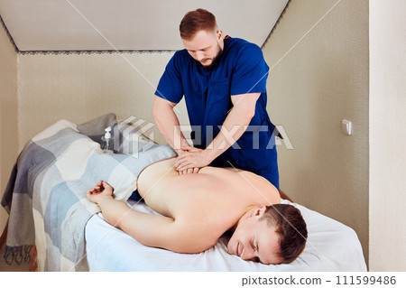 Man receives lower back massage at physiotherapist appointment. Man receives lower back massage at physiotherapist appointment. 111599486