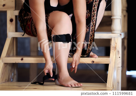 Woman tightens straps on posterior leaf spring ankle and foot orthotic, to prevent flaccid foot drop. Woman tightens straps on posterior leaf spring ankle and foot orthotic, to prevent flaccid foot drop. 111599681
