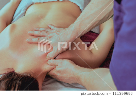 Neck muscle deep tissue massage, masseur places thumb pad on musculature that overlies laminar groove on right side. 111599693
