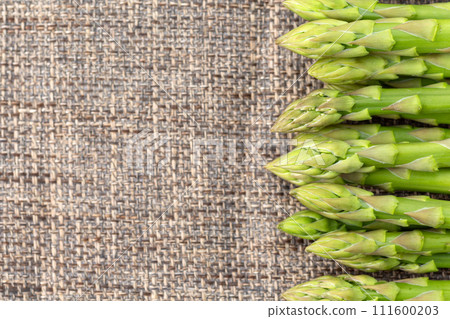 Green asparagus on brown linen background Green asparagus on brown linen background 111600203