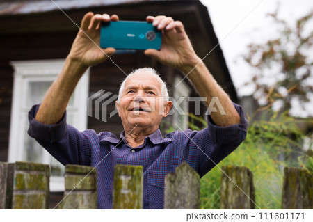 Senior man photographing with smartphone outdoors Senior man photographing with smartphone outdoors 111601171