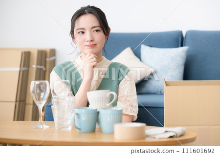 Close-up of a young woman worried while packing and preparing for moving Close-up of a young woman worried while packing and preparing for moving 111601692