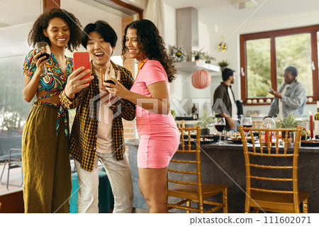 Smiling young friends taking selfie photo holding wine glasses on holiday dinner party at home Smiling young friends taking selfie photo holding wine glasses on holiday dinner party at home 111602071