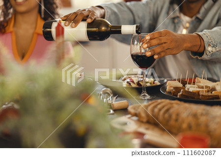 Close up of man pouring red wine into glass during festive dinner party 111602087