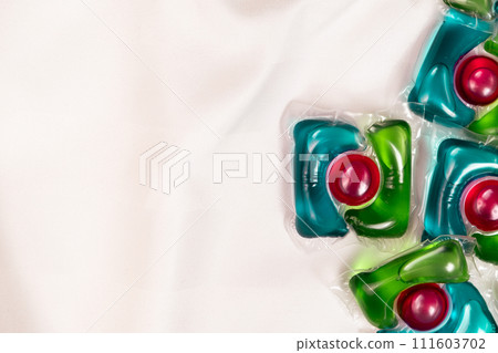 Lots of laundry pods capsule detergent on satin fabric, copy space for text. 111603702
