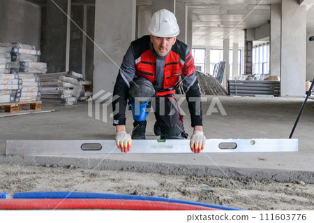 A foreman at a construction site in work clothes controls the work process, takes the necessary measurements 111603776