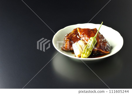 Teriyaki yellowtail, fried shishito and green onions photographed against a black background Teriyaki yellowtail, fried shishito and green onions photographed against a black background 111605244