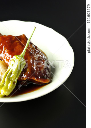 Teriyaki yellowtail, fried shishito and green onions photographed against a black background Teriyaki yellowtail, fried shishito and green onions photographed against a black background 111605279