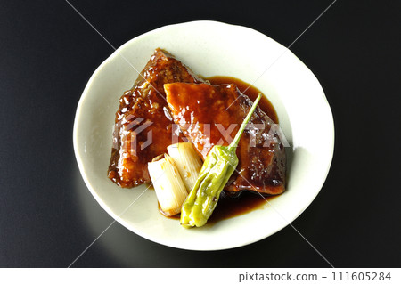 Overhead shot of yellowtail teriyaki and fried shishito and green onions against a black background 111605284