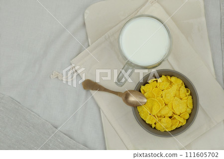 Breakfast cereals. Cornflakes in bowls and cup of milk on a light background. Fast food. Top view. 111605702