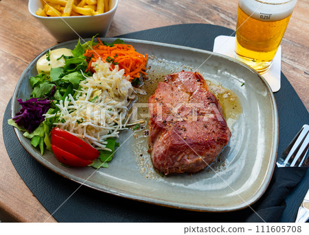 Pork (varkens cote) meat steak with vegetables salad on table Pork (varkens cote) meat steak with vegetables salad on table 111605708