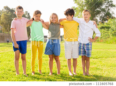 Happy tweenagers posing together on green lawn of city park Happy tweenagers posing together on green lawn of city park 111605768