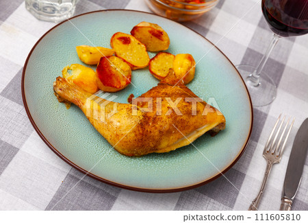 Barbecued chicken leg with boiled potatoes closeup on plate 111605810