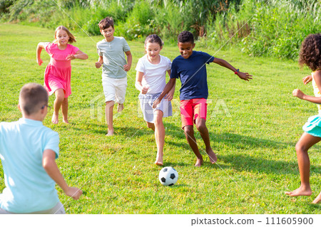 Kids running through grass and playing football Kids running through grass and playing football 111605900