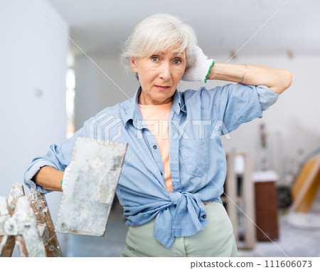 Portrait of positive woman with spatula in her hand in room being renovated Portrait of positive woman with spatula in her hand in room being renovated 111606073