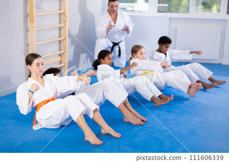 Teenagers performing core twist with punches during martial arts training 111606339