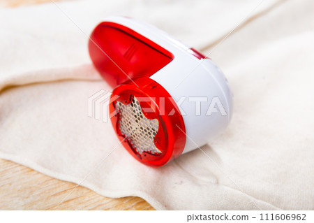 Fabric lint remover on white wool garment 111606962