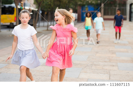 Two girls walking together outdoors 111607115