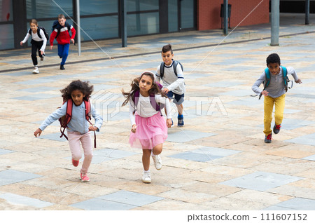 Group of cheerful tweenagers running in school yard after lessons 111607152