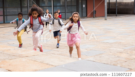 Happy schoolchildren running in the race from school outdoors Happy schoolchildren running in the race from school outdoors 111607227