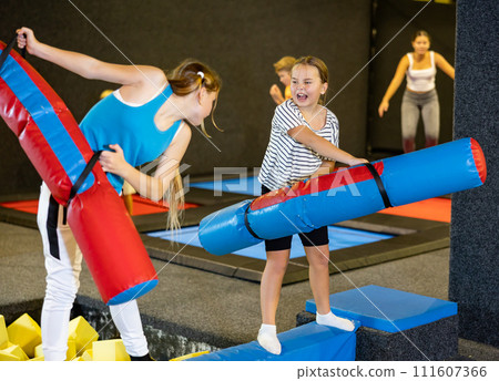 Preteen girl having fun on battle beam with other girl 111607366