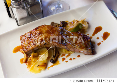 Baked under sauce tasty pork ribs at plate with mushrooms 111607524