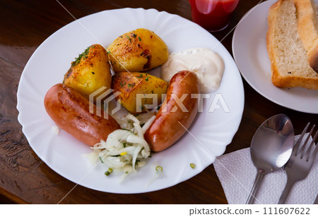 Roasted sausages served with baked potatoes and fried onion 111607622